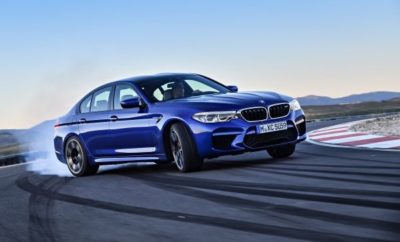 Η νέα BMW M5 (κατανάλωση μικτού κύκλου: 10,5 l/100 km*, εκπομπές CO2 στο μικτό κύκλο: 241 g/km *) προάγει τη BMW M GmbH σε ένα άλλο επίπεδο, καθώς το sedan υψηλών επιδόσεων αποκτά για πρώτη φορά σύστημα M xDrive AWD. Αυτή η νέα φιλοσοφία δίνει νέα διάσταση στις δυναμικές δυνατότητες της Μ5, αναβαθμίζοντας την καθημερινή πρακτικότητα σε όλες τις οδηγικές συνθήκες. Το νέο αυτοκίνητο έχει τις ρίζες του σε ένα πρωτότυπο – το πολυτελές τετράθυρο business sedan αγωνιστικού στυλ– που πρωτοείδαμε το 1984, με την πρώτη BMW M5. Το M xDrive που δημιούργησε η BMW M GmbH είναι το πιο συναρπαστικό σύστημα AWD στην κατηγορία υψηλών επιδόσεων. Χρησιμοποιεί κεντρικό κιβώτιο τετρακίνησης με πολύδισκο συμπλέκτη και κατανέμει την ισχύ μεταβλητά μεταξύ εμπρός και πίσω άξονα, ανάλογα με τις απαιτήσεις. Ένα ακόμα συστατικό κορυφαίας πρόσφυσης σε όλες τις οδικές και καιρικές συνθήκες είναι το Active M Differential στον πίσω άξονα, που επίσης λειτουργεί μεταβλητά και προσφέρει ποσοστό εμπλοκής από 0 έως 100%. Ο χαρακτήρας του M xDrive ρυθμίζεται σύμφωνα με τις επιθυμίες του οδηγού, που μπορεί να επιλέξει από πέντε διαφορετικά σεταρίσματα, ανάλογα με τους συνδυασμούς των DSC modes (DSC on, MDM, DSC off) και των M xDrive modes (4WD, 4WD Sport, 2WD). Στο βασικό σετάρισμα, με ενεργοποιημένο το DSC (Dynamic Stability Control) και 4WD, το σύστημα επιτρέπει ελαφρά ολίσθηση των πίσω τροχών κατά την επιτάχυνση στην έξοδο των στροφών – επομένως παίζει σημαντικό ρόλο στη σπορ ευελιξία της νέας BMW M5. Στο M Dynamic mode (MDM, 4WD Sport), το M xDrive επιτρέπει ελεγχόμενες υπερστροφές ισχύος (drifts). Τα τρία M xDrive modes με το DSC απενεργοποιημένο προορίζεται για ενθουσιώδεις οδηγούς και κυρίως για χρήση στην πίστα. Εδώ, ο οδηγός μπορεί να επιλέξει από τρία σεταρίσματα που περιλαμβάνουν και αμιγή πίσω κίνηση (2WD). Το συγκεκριμένο πρόγραμμα παρέχει δυνατότητα επιλογής της γωνίας ντριφταρίσματος, για γνήσια οδηγική απόλαυση. Τα πλούσια αποθέματα ισχύος της BMW M5 παράγει ένας κινητήρας 4.4L V8 bi-turbo, τεχνολογίας M TwinPower Turbo. Οι μηχανικοί του τμήματος M προχώρησαν σε σημαντικές βελτιώσεις του κινητήρα του απερχόμενου μοντέλου. Για παράδειγμα, νέοι υπερσυμπιεστές, υπέρ αποδοτική ψύξη αέρα υπερπλήρωσης και αυξημένη πίεση ψεκασμού καυσίμου αυξάνουν την ισχύ και κυρίως, τη ροπή. Ο κινητήρας αποδίδει 441 kW/600 hp στις 5.600 – 6.700 rpm, ενώ τεράστια ροπή 750 Nm είναι στη διάθεση του οδηγού από τις 1.800 rpm μόλις, και παραμένει διαθέσιμη μέχρι τις 5.600 rpm. Μία ηλεκτρονικά χαρτογραφημένη, αντλία λαδιού πλήρως μεταβλητής παροχής διασφαλίζει την απαιτούμενη τροφοδοσία στη νέα BMW M5, ακόμα και στην πίστα. Οι εντυπωσιακές επιδόσεις του αυτοκινήτου μιλάνε από μόνες τους: επιτάχυνση 0 - 100 km/h σε 3,4 δευτ., 0 - 200 km/h σε 11,1 δεύτερα. Η τελική ταχύτητα περιορίζεται στα 250 km/h από τον ηλεκτρονικό κόφτη, ενώ το προαιρετικό M Driver’s Package μπορεί να παρατείνει την απόλαυση μέχρι τα 305 km/h. Η νέα BMW M5 μεταφέρει όλη αυτή την κινητήρια ισχύ μέσω ενός ειδικά χαρτογραφημένου οκτατάχυτου κιβωτίου M Steptronic με Drivelogic. Σε D mode προσφέρει την άνεση και ευκολία των πλήρως αυτόματων αλλαγών σχέσεων, αλλά μπορεί να αλλάξει σε σειριακή λειτουργία με μηχανικές αλλαγές, μέσω του κομψού επιλογέα στην κεντρική κονσόλα ή των χειριστηρίων του τιμονιού (paddles). Με το Drivelogic, τα χαρακτηριστικά του κιβωτίου ρυθμίζονται σύμφωνα με τις προσωπικές προτιμήσεις του οδηγού. Για χρήση στην πίστα, το οκτατάχυτο M Steptronic αλλάζει ταχύτητες σαν αστραπή, προσφέροντας στη νέα BMW M5 εξαιρετική ευελιξία και δυναμική αίσθηση. Η ανάρτηση της νέας BMW M5 είναι ομοίως σχεδιασμένη με στόχο τη μέγιστη πρόσφυση σε καθημερινή χρήση και τις υψηλές δυναμικές επιδόσεις στην πίστα. Όπως ο κινητήρας, το κιβώτιο και το σύστημα M xDrive, το σύστημα βελτιώθηκε από ειδικούς και οδηγούς αγώνων, μεταξύ άλλων, στην πιο απαιτητική πίστα δοκιμών σε όλο τον κόσμο – στο Nürburgring Nordschleife. Προηγμένα ενισχυτικά στοιχεία μπροστά και πίσω, διασφαλίζουν μία εξαιρετικά άκαμπτη δομή αμαξώματος και άμεση πληροφόρηση από το αυτοκίνητο (feedback), κυρίως σε έντονα σπορ οδηγικό στυλ. Ο οδηγός μπορεί να επιλέγει μεταξύ των Comfort, Sport και Sport Plus modes για το σύστημα Variable Damper Control (VDC) – που έχει ρύθμιση ειδική για Μ – και το σύστημα διεύθυνσης M Servotronic. Τα χαρακτηριστικά του κινητήρα διαμορφώνονται σύμφωνα με τις προτιμήσεις του οδηγού μέσω των Efficient, Sport και Sport Plus modes. Μέσω των δύο μπουτόν M1 και M2 στο δερμάτινο τιμόνι M αποθηκεύονται δύο σεταρίσματα, συνδυάζοντας τις προτιμήσεις του οδηγού για κινητήρα, κιβώτιο και ανάρτηση και τα M xDrive mode, το DSC mode και τις ρυθμίσεις του Head-Up-Display. Ο οδηγός ενεργοποιεί το σετάρισμα που προτιμά πιέζοντας το σχετικό μπουτόν. Το αμάξωμα της νέας BMW M5 περιλαμβάνει αναβαθμίσεις σε σχέση με το στάνταρ μοντέλο της Σειράς 5, ώστε να ανταπεξέρχεται στις υψηλότερες προκλήσεις. Οι μηχανικοί του τμήματος M έχουν επανασχεδιάσει τα φαρδύτερα εμπρός πλαϊνά πάνελ και το ένθετο του εμπρός προφυλακτήρα, ώστε να συμπεριλάβουν μεγαλύτερα ανοίγματα για τον αέρα που τροφοδοτεί τα συστήματα ψύξης και τα φρένα. Νέος είναι και ο πίσω διαχύτης. Οι τέσσερις απολήξεις του συστήματος εξαγωγής υποδηλώνουν οπτικά την πλούσια ισχύ της BMW M5 και παράγουν τον κατάλληλο σπορ ήχο, μέσω των πεταλούδων ελέγχου. Ο οδηγός μπορεί με ένα μπουτόν να ρυθμίσει τον ήχο του κινητήρα σύμφωνα με τις επιθυμίες του. Το καπό, σχεδίασης Μ, κατασκευάζεται από αλουμίνιο και φέρει εντυπωσιακές ανάγλυφες γραμμές, που εκτείνονται μέχρι την οροφή από CFRP – στάνταρ στοιχείο της νέας M5. Με την μείωση βάρους που επιτυγχάνεται χάρη στην οροφή CFRP και άλλα εξαρτήματα όπως το σύστημα εξάτμισης, η νέα BMW M5 με M xDrive AWD είναι ελαφρύτερη από την προκάτοχό της. Η νέα BMW M5 φέρει στάνταρ συνθετικά φρένα M, που είναι ελαφρύτερα από τα αντίστοιχα από χυτοσίδηρο και επομένως μειώνουν το βάρος του αυτοκινήτου. Με μπλε εξαπίστονες δαγκάνες μπροστά και μονοπίστοντες πλευστές πίσω, συν διάτρητα, εσωτερικά αεριζόμενα δισκόφρενα παντού, τα συνθετικά φρένα M παρέχουν την ισχύ ακινητοποίησης που αρμόζει στις δυναμικές ικανότητες του αυτοκινήτου. Τα προαιρετικά carbon φρένα M, που αναγνωρίζονται από τις χρυσαφί δαγκάνες και εξοικονομούν επιπλέον 23 kg από το βάρος της M5, αντέχουν ακόμα σε πιο δύσκολες συνθήκες. Η νέα BMW M5 εξοπλίζεται στάνταρ με γυαλισμένες 19άρες ζάντες με πέντε διπλές ακτίνες (εμπρός: 9.5 x 19, πίσω: 10.5 x 19) σε Orbit Grey και ειδικά ελαστικά M (εμπρός: 275/40 R 19, πίσω: 285/40 R 19). Ζάντες 20 ιντσών διατίθενται προαιρετικά (εμπρός: ελαστικά 275/35 R 20 σε ζάντες 9.5 x 20, πίσω: ελαστικά 285/35 R 20 σε ζάντες 10.5 x 20). Ο στάνταρ εξοπλισμός της νέας BMW M5 περιλαμβάνει δερμάτινα καθίσματα Merino και M με ηλεκτρική ρύθμιση. Η λίστα προαιρετικών επιλογών περιέχει νέα καθίσματα Μ πολλαπλών λειτουργιών, με δομή τύπου μπάκετ και ακόμα καλύτερη πλευρική στήριξη. Η νέα BMW M5 θα διατίθεται για παραγγελία από το Σεπτέμβριο του 2017, στην τιμή των €117.900, και οι παραδόσεις θα ξεκινήσουν την άνοιξη του 2018. Την ημερομηνία που θα ξεκινήσουν οι πωλήσεις του στάνταρ μοντέλου M5, έχει προγραμματιστεί το λανσάρισμα της BMW M5 First Edition. Αυτή η ειδική έκδοση με περιορισμένη παρτίδα παραγωγής 400 οχημάτων σε όλο τον κόσμο – είναι βαμμένη σε BMW Individual Frozen Dark Red Metallic, φέρει αποκλειστικό εξοπλισμό και κοστίζει €19.500 επιπλέον σε σχέση με το στάνταρ μοντέλο.