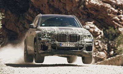 Τη μία μέρα η νέα BMW X5 βρίσκεται αντιμέτωπη με το ψύχος του αρκτικού κύκλου και την επομένη κάνει βόλτες στην πίστα του Nürburgring: Δοκιμάζοντας τη διάδοχο της σημερινής BMW X5, οι υπεύθυνοι εξέλιξης ελέγχουν αφενός την αντοχή, αφετέρου και την ευελιξία του νέου οχήματος. Το νέο Sports Activity Vehicle (SAV) περνά από ένα εξαιρετικά απαιτητικό και ποικίλο πρόγραμμα δοκιμών στο πλαίσιο της εξέλιξής του για μαζική παραγωγή. Τα πρωτότυπα της νέας BMW X5 καλούνται να αντέξουν σε κλιματικές ζώνες σε όλο τον κόσμο, αλλά και να ανταπεξέλθουν σε όλες τις εδαφικές συνθήκες. Εδώ η νέα τεχνολογία ανάρτησης πρέπει να αποδείξει τις ικανότητές της. Ως το πρώτο τετρακίνητο μοντέλο που γοήτευσε τους οδηγούς με τη διάσημη οδηγική απόλαυση BMW σε ορεινές διαδρομές και σε δρόμους ταχείας κυκλοφορίας, η πρώτη γενιά της BMW X5 έθεσε τα θεμέλια για μία νέα κατηγορία Sports Activity Vehicle πριν από σχεδόν δύο δεκαετίες. Στην προσεχή, τέταρτη γενιά της, τα πολλαπλά ταλέντα του μοντέλου θα αναδειχτούν περισσότερο από ποτέ. Σε αυτό συμβάλλει η υιοθέτηση νέων συστημάτων ανάρτησης και πλαισίου, που διατίθενται για πρώτη φορά σε μοντέλο BMW X και ουσιαστικά είναι μοναδικά στο περιβάλλον του ανταγωνισμού. Το νέο πακέτο offroad για παράδειγμα προσφέρει έναν εντυπωσιακό συνδυασμό κορυφαίας οδηγικής άνεσης στο δρόμο και δυνατότητα αλλαγής σεταρίσματος με το πάτημα ενός διακόπτη, για τέλεια προσαρμογή σε συνθήκες εκτός δρόμου. Ανεξάρτητα αν πατά σε χιόνι, άμμο, χαλίκι ή χώμα – η νέα BMW X5 έχει το τέλειο σύστημα κίνησης και σετάρισμα ανάρτησης για κάθε επιφάνεια. Τα πρωτότυπα απέδειξαν με πόση μαεστρία επιταχύνει, στρίβει και φρενάρει η νέα BMW X5 στο χειμερινό κέντρο δοκιμών στο Arjeplog, στη Σουηδία, στις χωμάτινες διαδρομές της Νότιας Αφρικής και στους αμμόλοφους στα ερημικά τοπία των ΗΠΑ. Επιβίωσαν σε υψηλές και χαμηλές θερμοκρασίες. Η νέα BMW X5 έπρεπε να αποδείξει τι αξίζει σε άνυδρα ορεινά εδάφη, τροπική υγρασία και λασπωμένες διαδρομές. Σε αυτές τις δοκιμές αντοχής προστέθηκαν και άλλες που πραγματοποιήθηκαν στις εγκαταστάσεις της BMW στο Miramas στη Νότια Γαλλία, στην πίστα υψηλών ταχυτήτων στην Talladega στην Alabama και στην πίστα δοκιμών του Nürburgring στη Γερμανία που ήταν εξίσου σημαντικές, για να υπάρχει μία ολοκληρωμένη εικόνα επιδόσεων. Οι πληροφορίες και τα συμπεράσματα που αποκτήθηκαν δείχνουν ότι η νέα BMW X5 πληροί τις υψηλότερες απαιτήσεις σε ό,τι αφορά την ευελιξία, την ακρίβεια, τον έλεγχο και την άνεση, κυρίως χάρη στο Adaptive M Suspension Professional και το Integral Active Steering, που επίσης προσφέρεται για πρώτη φορά.