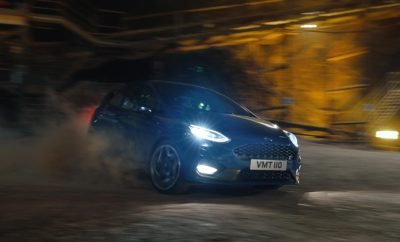 Η υπεροχή κι οι επιδόσεις του νέου Ford Fiesta ST καταγράφονται σε ένα νέο βίντεο που φέρνει στο φως μία εντυπωσιακή διαδρομή – 400 μέτρα κάτω από το έδαφος σε ένα από τα μεγαλύτερα Ευρωπαϊκά αλατωρυχεία. Γυρισμένο σε ία μυστική τοποθεσία με οδηγό τον Παγκόσμιο Πρωταθλητή Ράλι Elfyn Evans, το Fiesta ST εμφανίζεται να γλιστράει, να πλαγιολισθαίνει και να απογειώνεται στο χώμα. Ο ήχος 200 PS από τον EcoBoost του 1.5 λίτρου ενισχύεται από τα τοιχώματα των στοών καθώς περνά με ιλιγγιώδη ταχύτητα την στενή είσοδο της σήραγγας. “Οδηγικά, το αλάτι είναι ουσιαστικά σαν το καλοστρωμένο χώμα, αρκετά ολισθηρό για να είμαι ειλικρινής, ειδικά με λάστιχα δρόμου,” είπε ο Evans. “Αν και περιμένεις να είναι κλειστοφοβικό, αποδεικνύεται ακριβώς το αντίθετο, το τέλειο μέρος για να απολαύσεις το νέο Fiesta ST”. Η σειρά της Ford Καλύτεροι Ευρωπαϊκοί Αυτοκινητόδρομοι φέρνει τα οχήματα υψηλών επιδόσεων –μεταξύ των οποίων Ford GT, Ford Focus RS και Ford Mustang Convertible σε μερικά από τα πιο εντυπωσιακά τοπία της ηπειρωτικής Ευρώπης – από τον Αρκτικό Κύκλο στη Νορβηγία στην ηλιόλουστη Μαγιόρκα. Μέχρι τώρα, όλες οι τοποθεσίες ήταν επίγειες. Η Ford επέλεξε το μυστικό αλατ0ρυχείο για το νέο τηλεοπτικό spot με τίτλο ‘Undertrack’ όπου το αυτοκίνητο περιφέρεται μέσα στο δίκτυο στοών μήκους 60 χλμ., σε σταθερή θερμοκρασία 16 C κάτω από αυστηρά μέτρα προστασίας που περιόρισαν στο ελάχιστο τα μέλη του κινηματογραφικού συνεργείου για το τριήμερο γύρισμα. Παρακολουθήστε το βίντεο με το Fiesta ST στο ορυχείο: https://youtu.be/tI6xLRwr_hA Δείτε το διαφημιστικό spot ‘Undertrack’: https://youtu.be/6HuAHLToqvg “Το υποβλητικό σκηνικό των υπόγειων στοών και μαζί η ευκαιρία να δείξουμε τις δυνατότητες του Fiesta ST σε διαφορετικούς τύπους επιφανειών είχαν την μεγαλύτερη βαρύτητα στην επιλογή αυτής της μοναδικής τοποθεσίας”, κατά τον Leo Roeks, διευθυντή της Ford Performance. “Δεν ήταν μια τυπική πίστα, ήταν ένα μέρος που μπορούσαμε να οδηγήσουμε το σπουδαίο Fiesta στο μέγιστο των δυνατοτήτων του”.