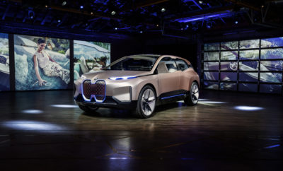 Το BMW Vision iNEXT αποτυπώνει το όραμα της μελλοντικής μετακίνησης. Το τελευταίο Vision Vehicle του BMW Group συμβολίζει το ξημέρωμα μιας νέας εποχής στην οδηγική απόλαυση – και γιορτάζει την παγκόσμια πρεμιέρα του στο Σαλόνι Αυτοκινήτου του Λος Άντζελες. Δεν πρόκειται για ένα απλό αυτοκίνητο: το BMW Vision iNEXT θέτει τις βάσεις για το μέλλον του BMW Group, με τεχνολογίες, σχεδιαστικά στοιχεία και καινοτομίες που θα ενσταλαχτούν στην εταιρία και τις μάρκες της. Είναι η πρώτη φορά που όλοι οι στρατηγικοί τομείς καινοτομίας του BMW Group – Αυτόνομη Οδήγηση, Συνδεσιμότητα, Εξηλεκτρισμός και Υπηρεσίες (ACES - Autonomous driving, Connectivity, Electrification and Services) – ενσωματώνονται σε ένα αυτοκίνητο και εκφράζονται μέσω της σχεδίασης (D+ACES) διαμορφώνοντας το μελλοντικό πρόσωπο της οδηγικής απόλαυσης. Ανθρωποκεντρική σχεδίαση . Η μετακίνηση αποτελεί εγγενές στοιχείο της ζωής, των εμπειριών μας και της αισθητηριακής μας οντότητας. Με λίγα λόγια είναι βασική, ανθρώπινη ανάγκη. Συνεπώς, σκεπτόμενοι το μέλλον της μετακίνησης, στο επίκεντρο βρίσκονται περισσότερο από ποτέ οι άνθρωποι, τα συναισθήματα, και οι ανάγκες / προτιμήσεις για μετακίνηση. Οι δυνατότητες που προσφέρουν η αυτόνομη οδήγηση, ο εξηλεκτρισμός και η προηγμένη συνδεσιμότητα θα οδηγήσουν σε νέες εμπειρίες και νέους τρόπους προγραμματισμού ταξιδιών με αυτοκίνητο. Ταυτόχρονα, υπόσχονται να αλλάξουν τις επιθυμίες μας και τις καθημερινές μας συνήθειες. Μία ‘ μπουτίκ ’ σε τροχούς . Οι οδηγοί θα έχουν μέγιστη ελευθερία να αποφασίζουν πώς επιθυμούν να αξιοποιούν το χρόνο τους κατά τη διάρκεια του ταξιδιού. Η σχεδίαση εσωτερικού θα αποκτά διαρκώς μεγαλύτερη σημασία, με τον παράγοντα ‘ευεξίας’ να παίζει πρωταρχικό ρόλο. Γι’ αυτό, το BMW Vision iNEXT δημιουργήθηκε σαν ένας νέος “αγαπημένος χώρος” σε τροχούς, που παρέχει αληθινή ποιότητα ζωής και όπου μπορούμε να λειτουργούμε ελεύθερα και να χαλαρώνουμε.Έτσι, η σχεδίαση απευθύνεται άμεσα στο συναίσθημα και μεταφέρει μία αίσθηση θετικότητας, κατά την είσοδο στο όχημα. Η γεωμετρία της καμπίνας του iNEXT αποτελεί μία σύνθεση καθαρών, απέριττων γραμμών, με έμφαση στα υλικά και τα χρώματα. Ο συνδυασμός υφάσματος και ξύλου δημιουργεί μία σοφιστικέ αίσθηση που παραπέμπει σε ντιζάιν επίπλων, χαρίζοντας στο εσωτερικό τον ξεχωριστό χαρακτήρα μιας ‘μπουτίκ’. Η καμπίνα κατακλύζεται από ζεστά, φιλόξενα χρώματα, όπως οι nude αποχρώσεις Purus Rosé, Brown και Beige, ενώ η ιριδίζουσα μεταλλική Mystic Bronze αναδεικνύει τη συνολική εικόνα. Στο πίσω τμήμα κυριαρχεί η υφασμάτινη ταπετσαρία Enlighted Cloudburst σε πετρόλ απόχρωση, με περίπλοκη ύφανση ζακάρ (Jacquard), που διατρέχει ασύμμετρα την έδρα του καθίσματος και εκτείνεται στα πλαϊνά πάνελ και το ράφι. Ευφυείς τεχνολογίες που ‘δρουν’ στο παρασκήνιο. Οι ευφυείς τεχνολογίες θα βοηθούν τον άνθρωπο ακόμα πιο διακριτικά στο μέλλον. Στο BMW Vision iNEXT, οι τεχνολογίες αυτές παραμένουν στο παρασκήνιο χωρίς να υποδηλώνουν την παρουσία τους – εξ ου και η ονομασία Shy Tech – και ενεργοποιούνται μόνον όταν είναι απαραίτητες, ή κατόπιν εντολής του οδηγού ή των επιβατών. Οθόνες ή διακόπτες περιττεύουν. Η διαχείριση των λειτουργιών γίνεται μέσω επιφανειών από ξύλο ή ύφασμα, όπως η υφασμάτινη ταπετσαρία Jacquard στο BMW Vision iNEXT. Επομένως, ο έλεγχος του αυτοκινήτου προσαρμόζεται πλήρως στις απαιτήσεις οδηγού και επιβατών. Εξωτερικό: ακρίβεια και σαφήνεια. Το εξωτερικό του BMW Vision iNEXT ξεχειλίζει ομοίως από καινοτομίες. Η νέα σχεδιαστική γλώσσα BMW i δίνει δυναμικά το παρών με εντυπωσιακές γραμμές και καθαρές φόρμες, συμπεριλαμβανομένων των έντονα ανάγλυφων επιφανειών που καμπυλώνονται γύρω από τα ‘πλευρά’, θυμίζοντας ‘γράμμωση’ αθλητή. Η συναρπαστική απόχρωση Liquid Greyrose Copper σταδιακά αλλάζει από ένα ζεστό τόνο του χαλκού (warm copper) σε σκούρο τριανταφυλλί (dark rose) και αποπνέει έναν αχαλίνωτο δυναμισμό για ακόμα πιο εντυπωσιακό εξωτερικό. Το BMW Vision iNEXT υιοθετεί μία πολύ μοντέρνα εκδοχή του κλασικού εμπρός τμήματος με τα τέσσερα μάτια της BMW, όπου εντάσσονται πολύ λεπτοί προβολείς, ενώ κάμερες (αντί εξωτερικοί καθρέφτες) δείχνουν τι συμβαίνει πίσω. Το παρμπρίζ συγχωνεύεται στη μεγάλη πανοραμική οροφή, μέσα από την οποία φαίνεται καθαρά το καινοτόμο εσωτερικό του αυτοκινήτου. Πίσω, η οριζόντια διάταξη γραμμών και επιφανειών δημιουργεί ένα φαρδύ και δυναμικό στήσιμο, ενώ τα λεπτά πίσω φώτα συνεχίζονται στο πίσω τμήμα του αυτοκινήτου. Ο αέρας ρέει κατά μήκος της οροφής του BMW Vision iNEXT μέχρι το πίσω άκρο, που σε συνδυασμό με ένα φωτιζόμενο διαχύτη βελτιώνει την αεροδυναμική του αυτοκινήτου. Ο διαχύτης είναι ένα ελκυστικό στιλιστικό στοιχείο και άκρως λειτουργικό: εκτός από τη θετική του επίδραση στην αεροδυναμική του Vision Car, αυξάνει και την ηλεκτρική αυτονομία. Εμπνευσμένος από αγωνιστικά αυτοκίνητα, ο διαχύτης επισημαίνει την σπορ παρουσία BMW – χωρίς να φαίνεται ούτε μία απόληξη εξαγωγής. Παγκόσμια πρεμιέρα στην Καλιφόρνια. Το BMW Vision iNEXT γιορτάζει την παγκόσμια πρεμιέρα του στο Σαλόνι Αυτοκινήτου του Λος Άντζελες 2018. Το Vision Car του BMW Group προαναγγέλλει το ξεκίνημα μιας νέας εποχής στην οδηγική απόλαυση και σηματοδοτεί το επόμενο βήμα για τη συνεχιζόμενη προϊοντική επέλαση της εταιρίας του Μονάχου. Το μοντέλο παραγωγής BMW iNEXT θα κατασκευάζεται στο Εργοστάσιο του Dingolfing από το 2021, ως η νέα τεχνολογική ναυαρχίδα που θα μεταφέρει τους στρατηγικούς τομείς καινοτομίας της εταιρίας (D+ACES) στο δρόμο.